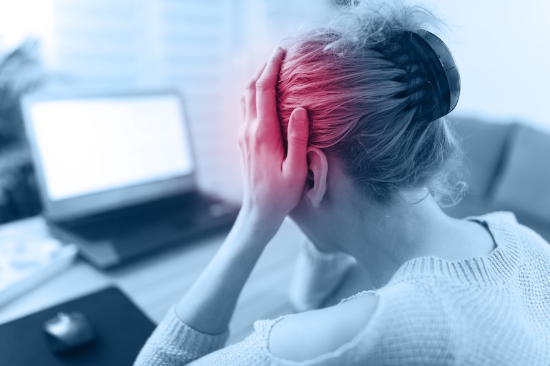 Woman experiencing stress while working at a laptop